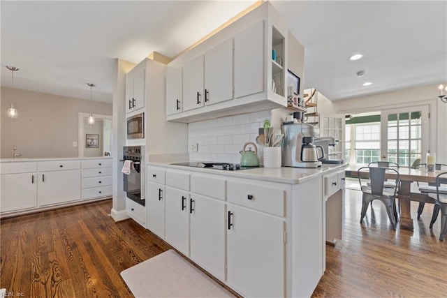 kitchen with black appliances, decorative backsplash, white cabinets, and hanging light fixtures