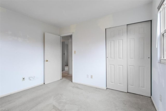 unfurnished bedroom with light carpet and a closet