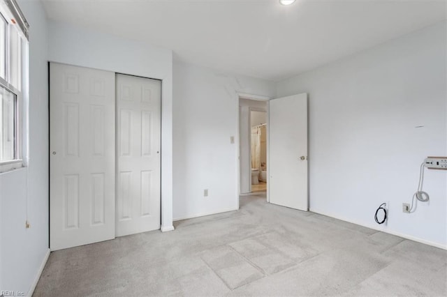 unfurnished bedroom featuring multiple windows, light colored carpet, and a closet