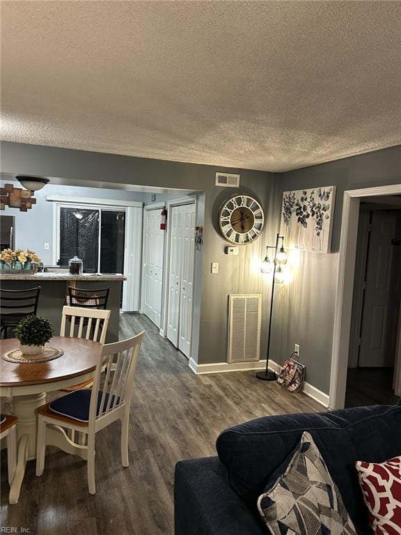 dining room with wood-type flooring and a textured ceiling