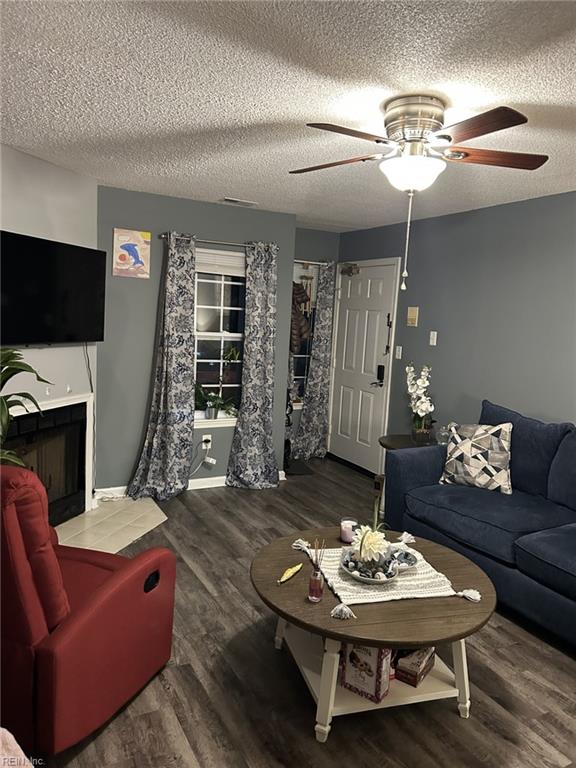 living room with ceiling fan, dark hardwood / wood-style flooring, and a textured ceiling