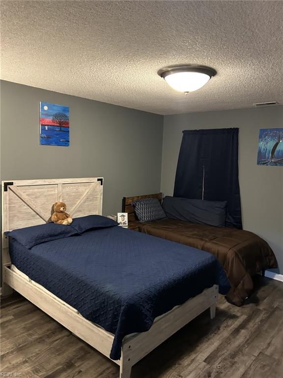 bedroom featuring dark hardwood / wood-style flooring and a textured ceiling