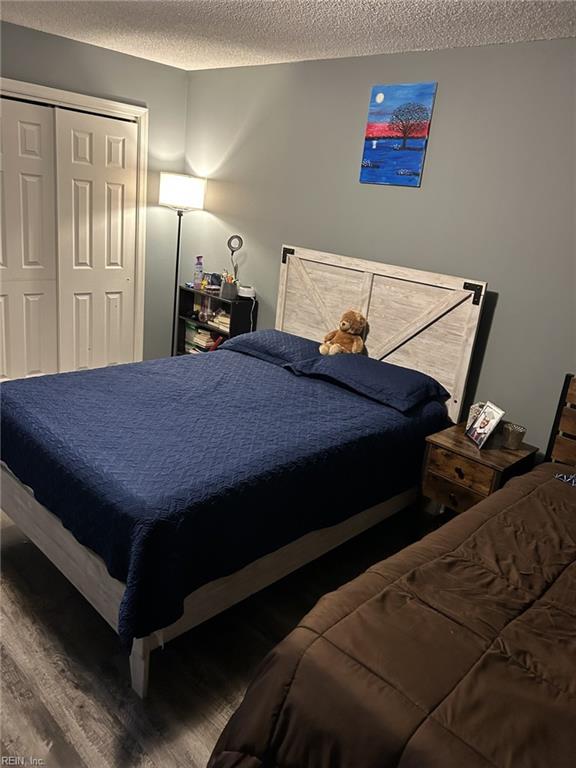 bedroom with hardwood / wood-style floors, a textured ceiling, and a closet