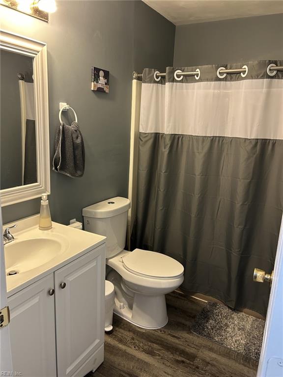 bathroom featuring a shower with shower curtain, vanity, wood-type flooring, and toilet