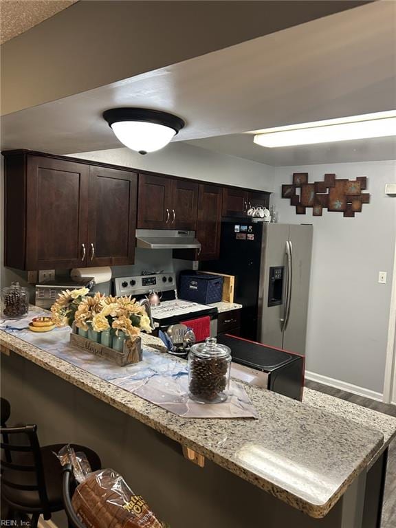 kitchen featuring range with electric stovetop, stainless steel fridge with ice dispenser, dark brown cabinets, and a breakfast bar area