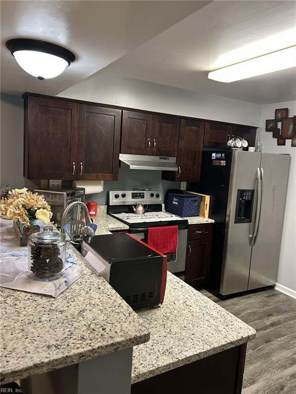 kitchen featuring sink, dark brown cabinetry, light stone counters, wood-type flooring, and stainless steel appliances