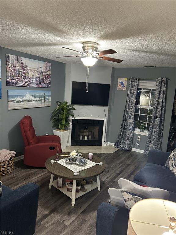 living room with hardwood / wood-style floors, ceiling fan, and a textured ceiling