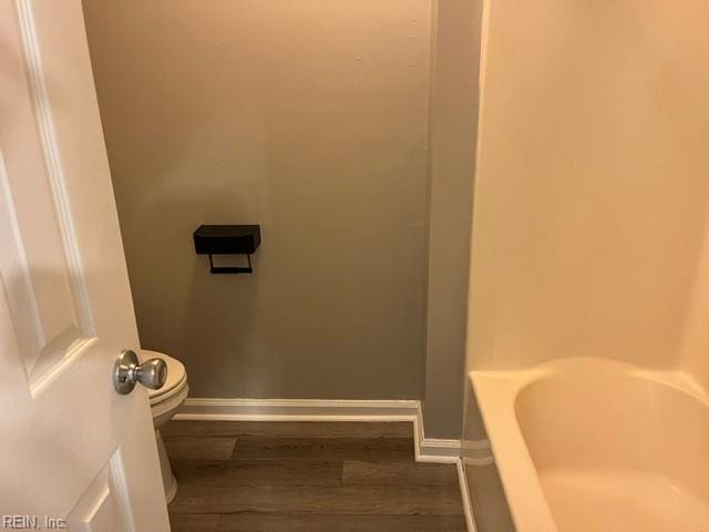 bathroom with wood-type flooring, toilet, and a tub