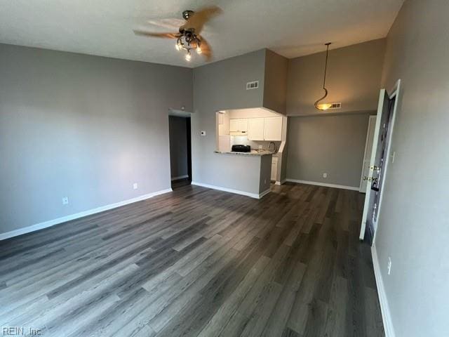 unfurnished living room featuring a high ceiling, dark hardwood / wood-style flooring, and ceiling fan