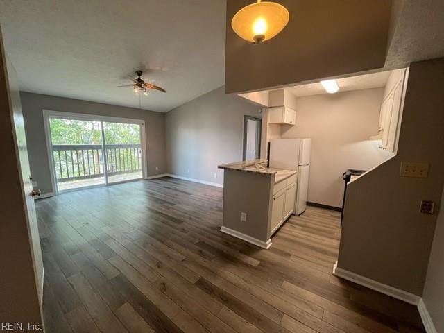 kitchen featuring light stone countertops, white refrigerator, white cabinetry, and dark wood-type flooring