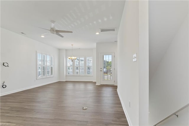 empty room with dark hardwood / wood-style floors and ceiling fan with notable chandelier