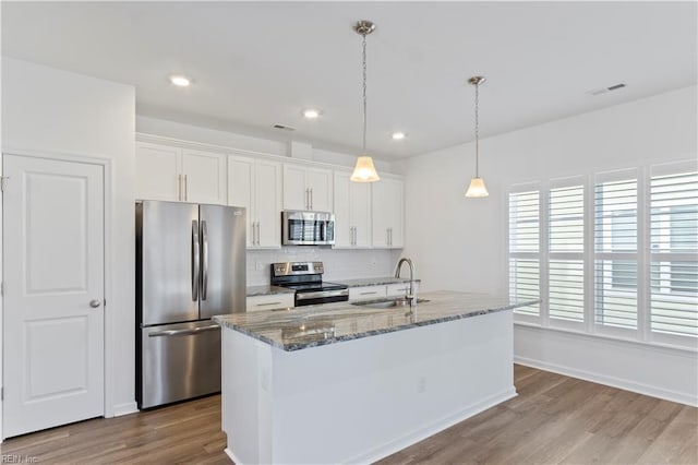 kitchen with appliances with stainless steel finishes, white cabinetry, dark stone counters, and sink