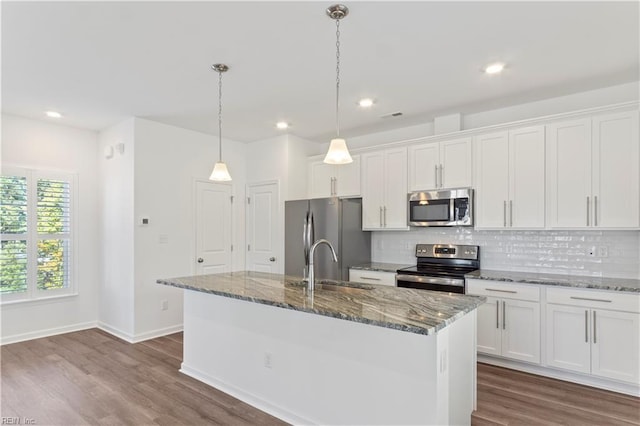 kitchen featuring backsplash, white cabinetry, a center island with sink, and appliances with stainless steel finishes