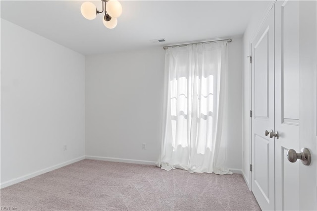 carpeted spare room with a notable chandelier