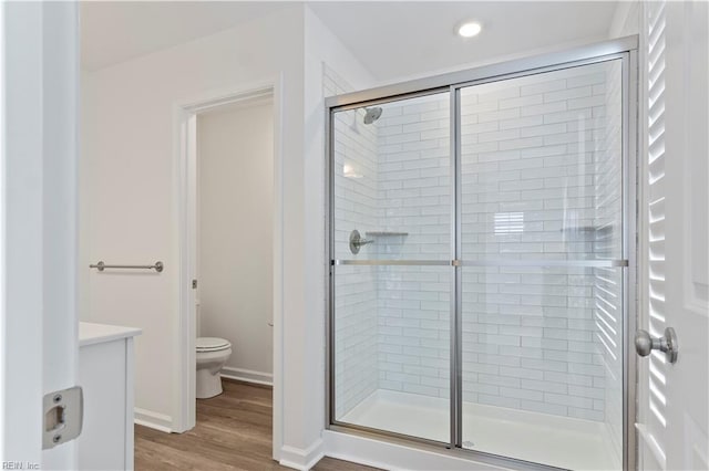 bathroom with hardwood / wood-style floors, vanity, an enclosed shower, and toilet