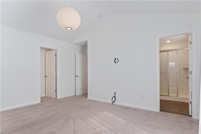 carpeted empty room featuring vaulted ceiling