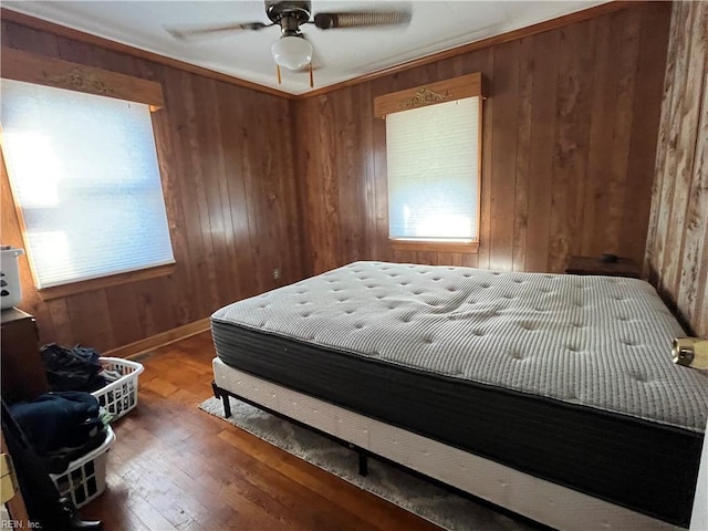 bedroom featuring ceiling fan, wood-type flooring, and wood walls