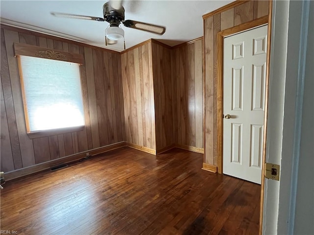 spare room with ceiling fan, wooden walls, and dark hardwood / wood-style floors