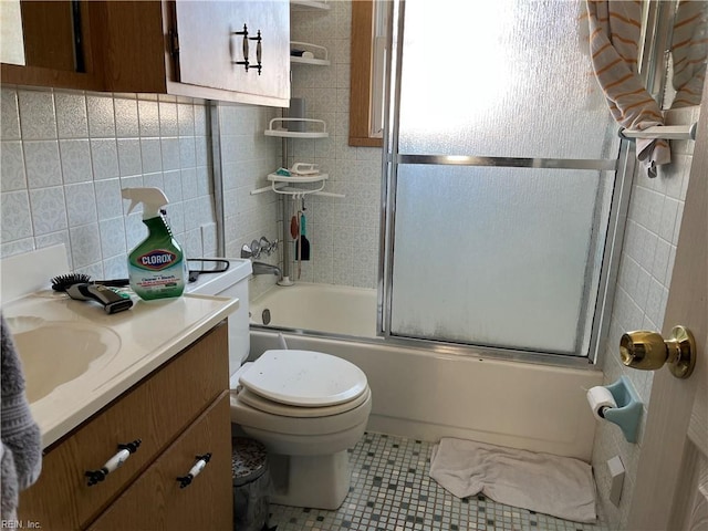 full bathroom with tile patterned flooring, combined bath / shower with glass door, toilet, vanity, and tile walls