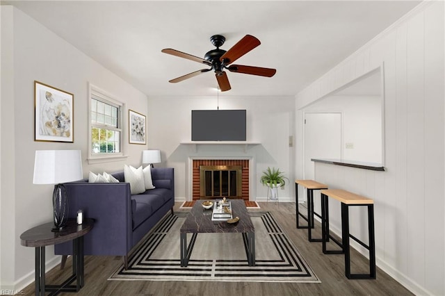 living room with dark hardwood / wood-style floors, a brick fireplace, and ceiling fan