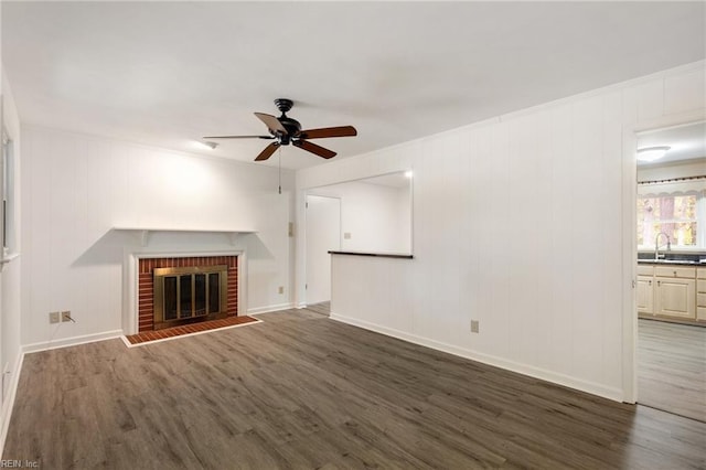 unfurnished living room featuring a fireplace, dark hardwood / wood-style floors, ceiling fan, and sink