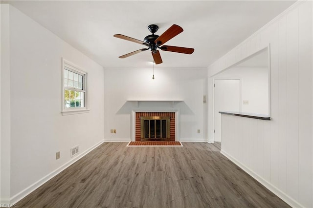 unfurnished living room featuring ceiling fan, dark wood-type flooring, and a brick fireplace