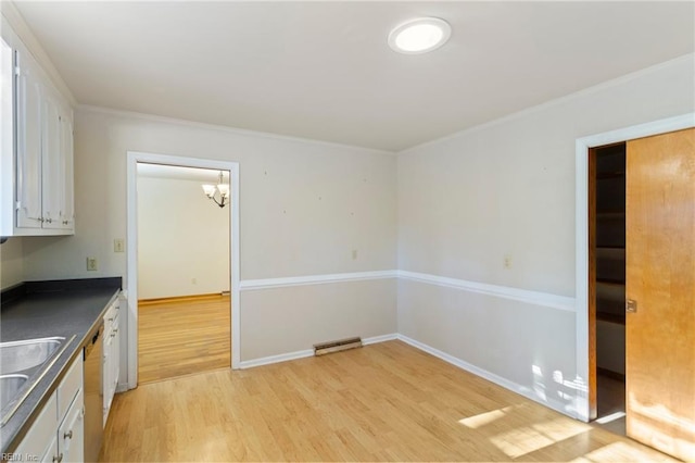 kitchen with white cabinetry, an inviting chandelier, ornamental molding, and light wood-type flooring