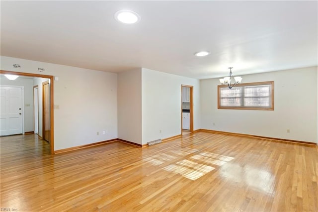 unfurnished room with hardwood / wood-style floors and a notable chandelier