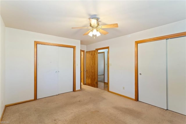 unfurnished bedroom with light carpet, two closets, and ceiling fan