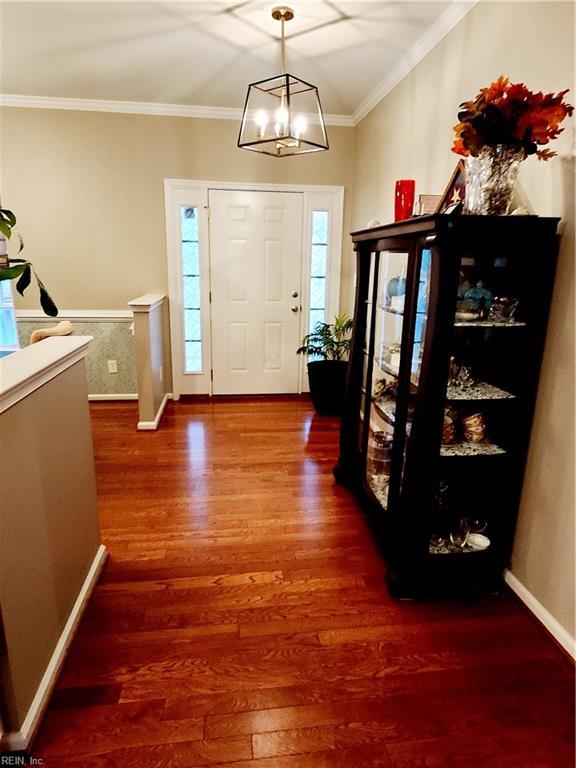 entryway featuring wood-type flooring, ornamental molding, and a chandelier