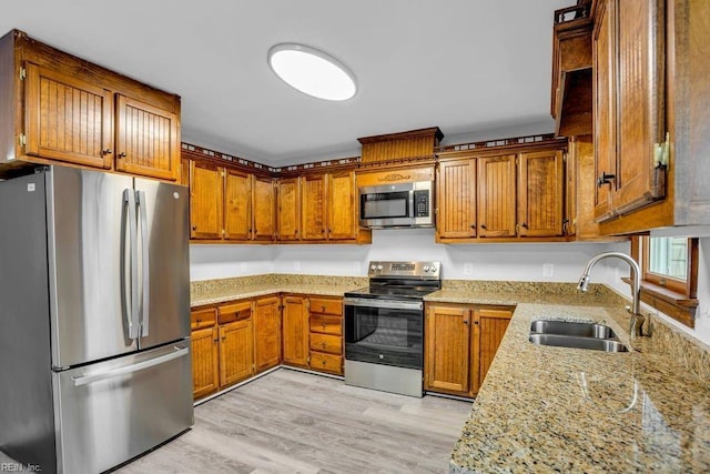 kitchen featuring light stone counters, light hardwood / wood-style floors, sink, and stainless steel appliances