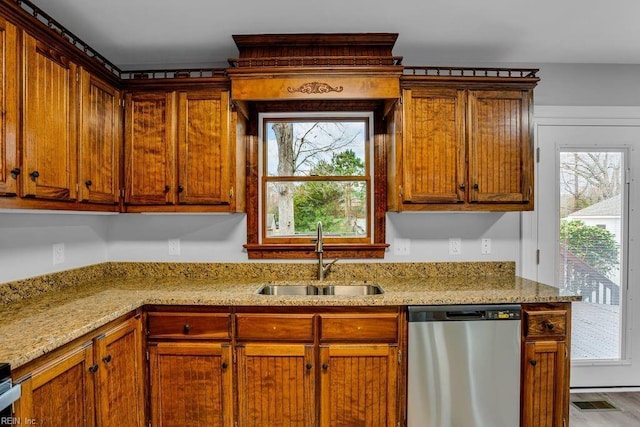 kitchen with stainless steel dishwasher, light stone counters, and sink