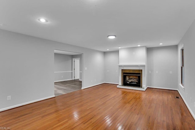 unfurnished living room with a tile fireplace and hardwood / wood-style floors