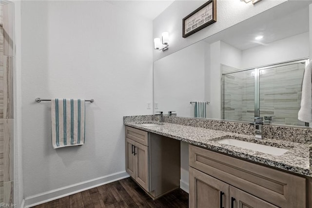 bathroom with hardwood / wood-style flooring, vanity, and a shower with door