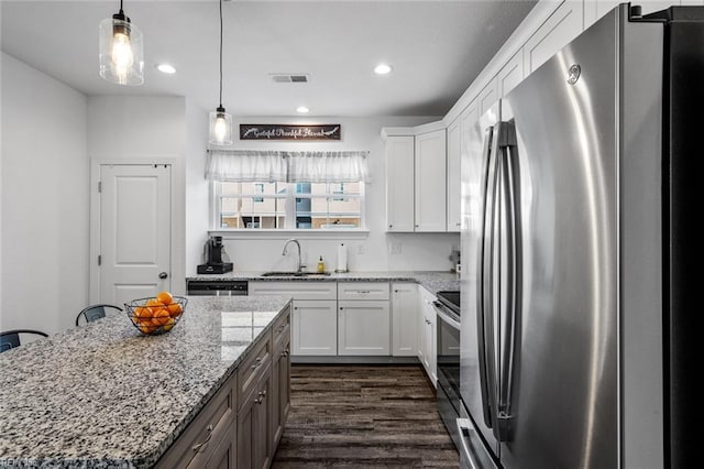 kitchen featuring white cabinets, sink, appliances with stainless steel finishes, decorative light fixtures, and a kitchen island