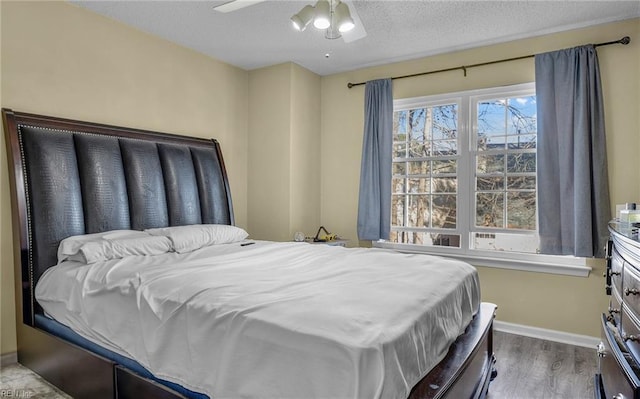 bedroom featuring hardwood / wood-style floors, ceiling fan, and a textured ceiling