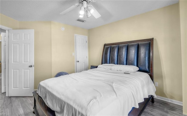 bedroom with ceiling fan, wood-type flooring, and a textured ceiling