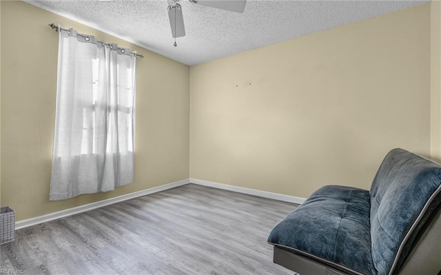 sitting room featuring ceiling fan, a textured ceiling, and light hardwood / wood-style flooring