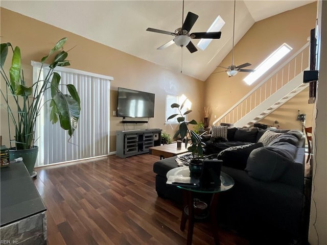 living room featuring plenty of natural light, lofted ceiling with skylight, ceiling fan, and dark wood-type flooring