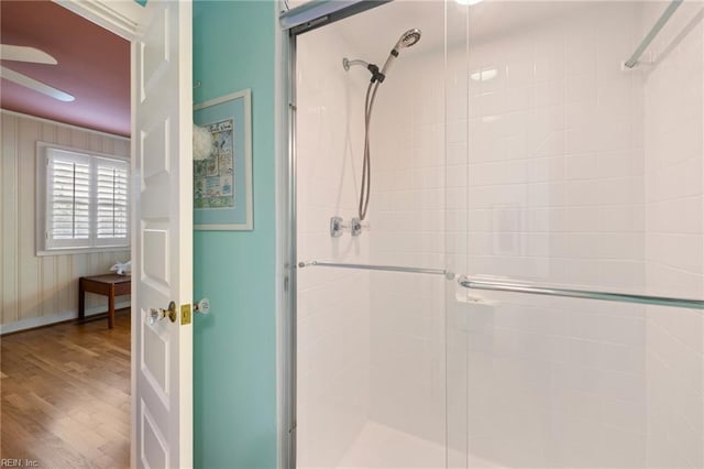 bathroom with wood-type flooring, ceiling fan, and a shower with shower door