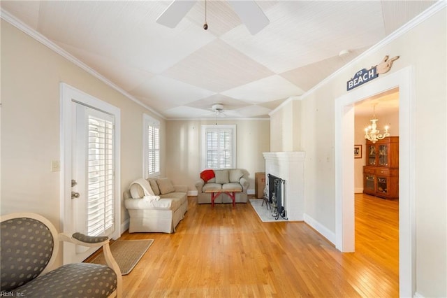 living area featuring crown molding, ceiling fan with notable chandelier, and light wood-type flooring