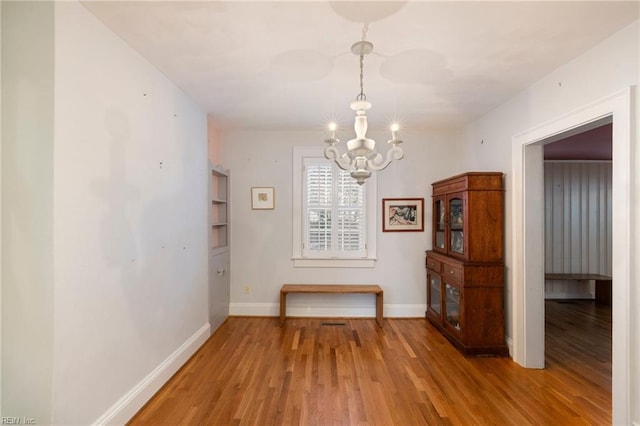 unfurnished dining area featuring wood-type flooring and an inviting chandelier