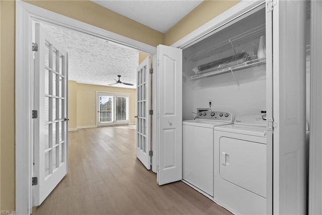 clothes washing area featuring ceiling fan, washing machine and dryer, a textured ceiling, light wood-type flooring, and french doors