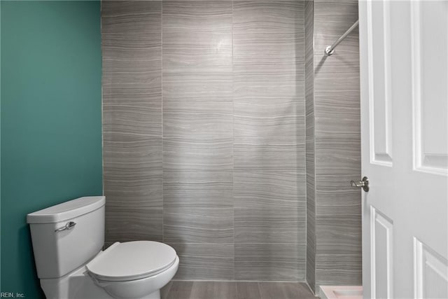 bathroom with tiled shower and toilet