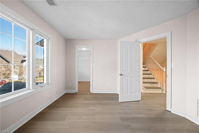 unfurnished room with plenty of natural light, a textured ceiling, and light wood-type flooring