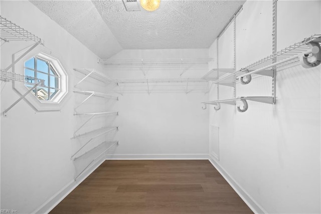 walk in closet with dark hardwood / wood-style flooring and lofted ceiling