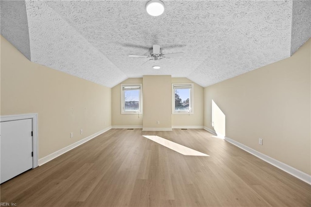 additional living space with hardwood / wood-style flooring, ceiling fan, lofted ceiling, and a textured ceiling