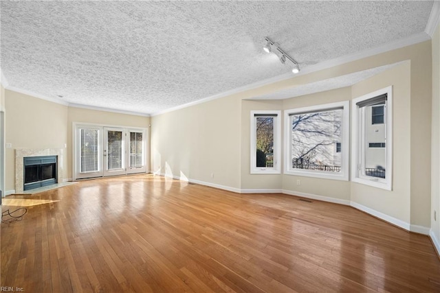 unfurnished living room with crown molding, wood-type flooring, track lighting, and a fireplace