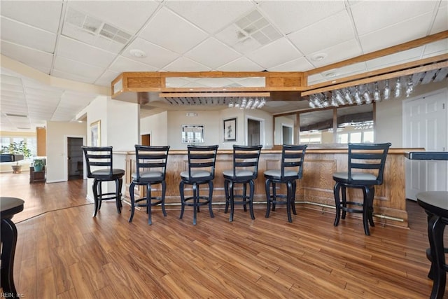 bar with hardwood / wood-style flooring and a paneled ceiling