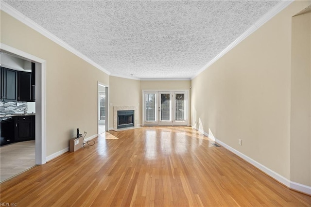 unfurnished living room featuring ornamental molding, a textured ceiling, and light hardwood / wood-style flooring